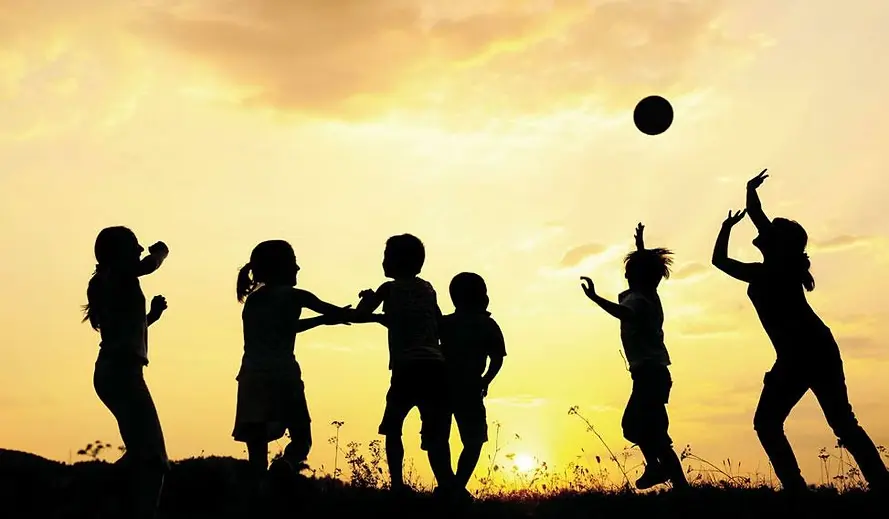 Children playing ball in sunset